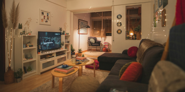 Cozy living room with a 4K TV displaying a movie, showcasing a comfortable setting with colorful pillows, books, plants, and soft lighting, perfect for streaming with a 4K wireless HDMI transmitter and receiver.
